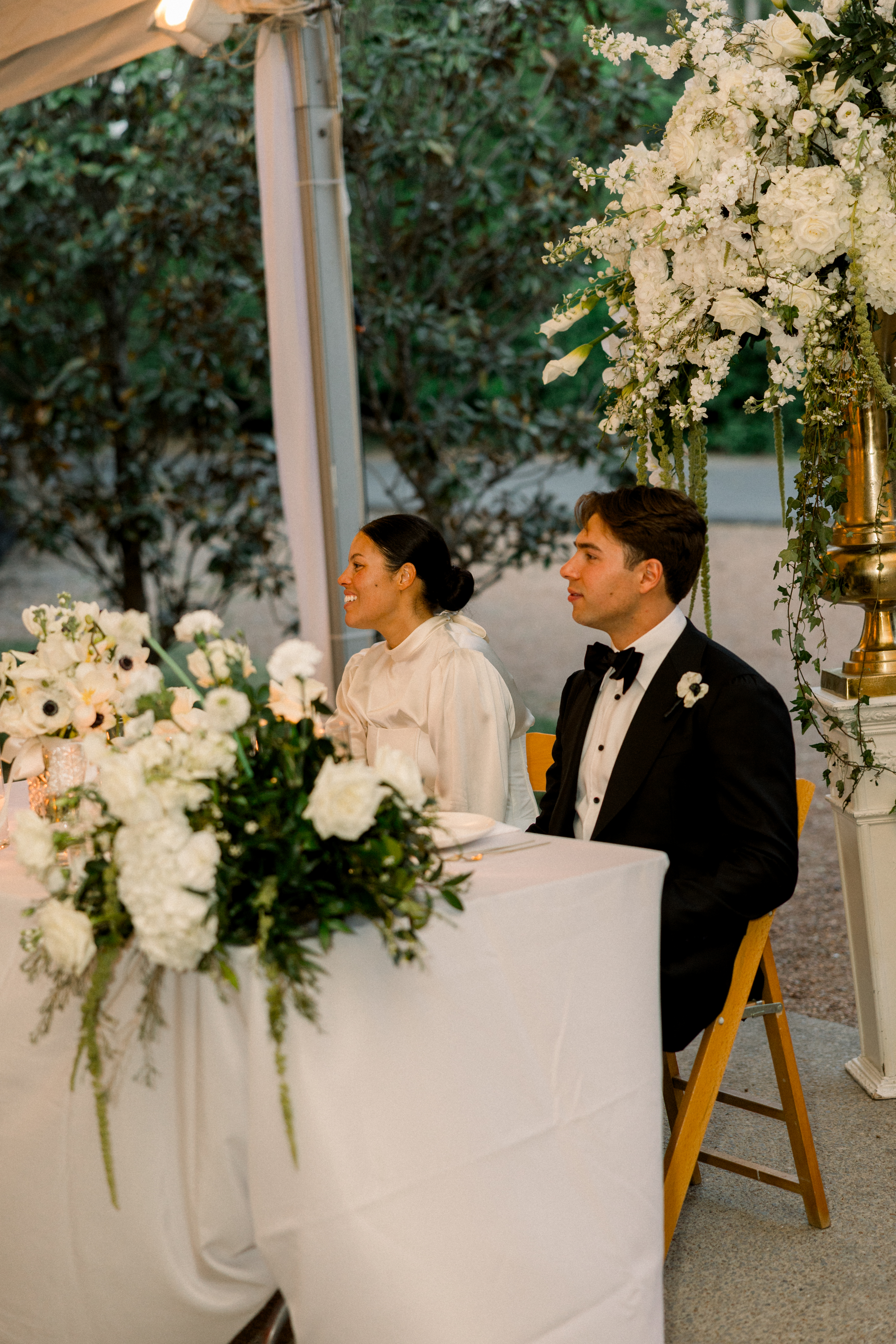 the bride and groom sitting behind a table