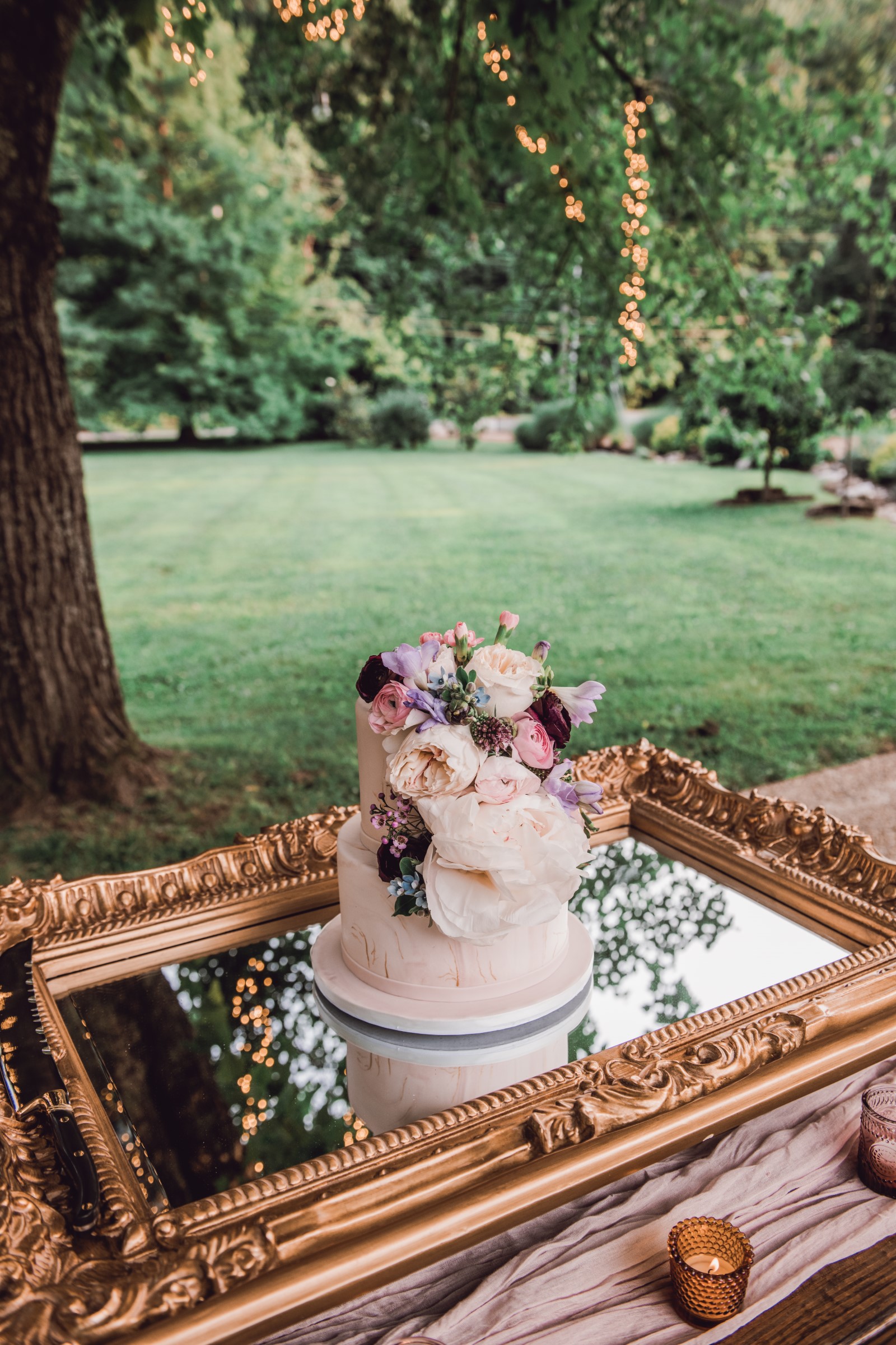 a light pink cake decorated with roses and on top of a mirror