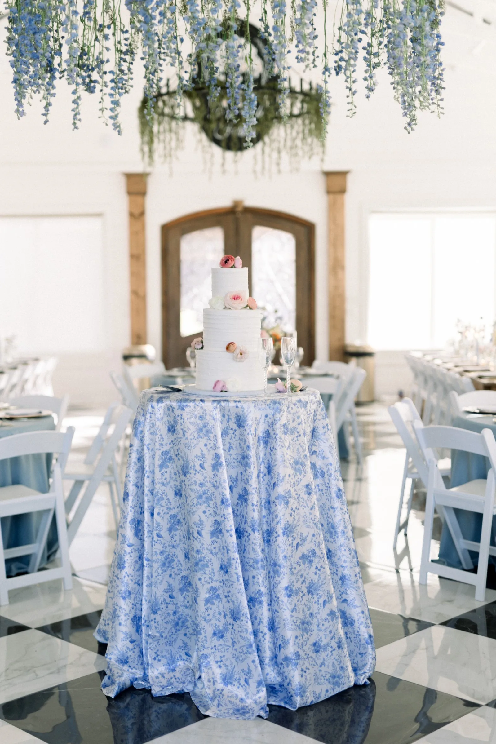 a white cake decorated with petals on a blue floral table