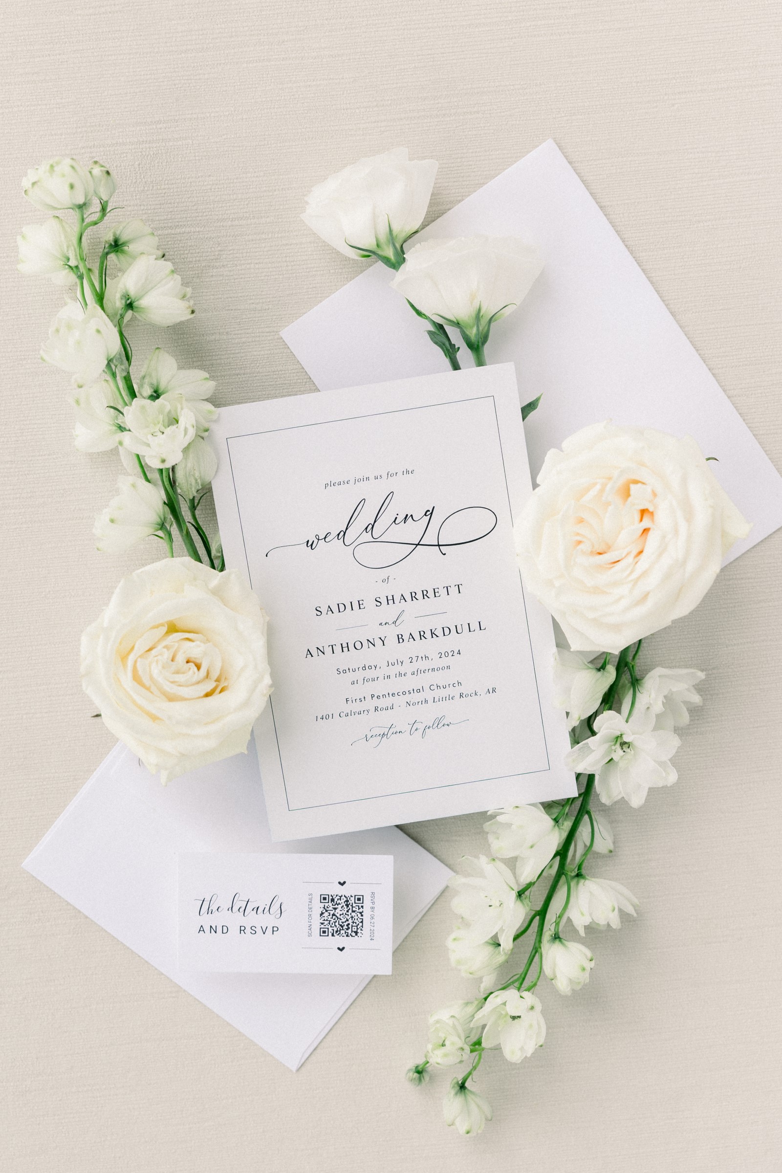 a wedding invitation card surrounded by two cream colored roses